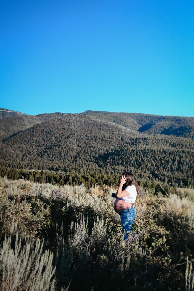 Pregnant mama standing in field being photographed during her driggs maternity session