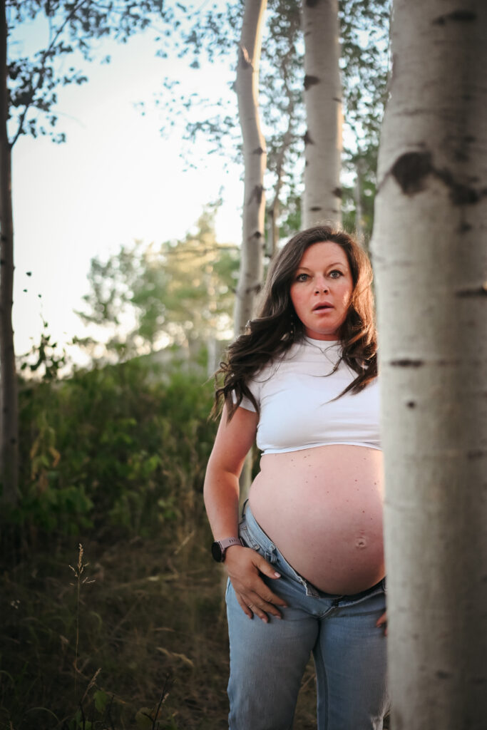 Radiant Mama-to-be standing next to a tree during her Driggs Maternity Session