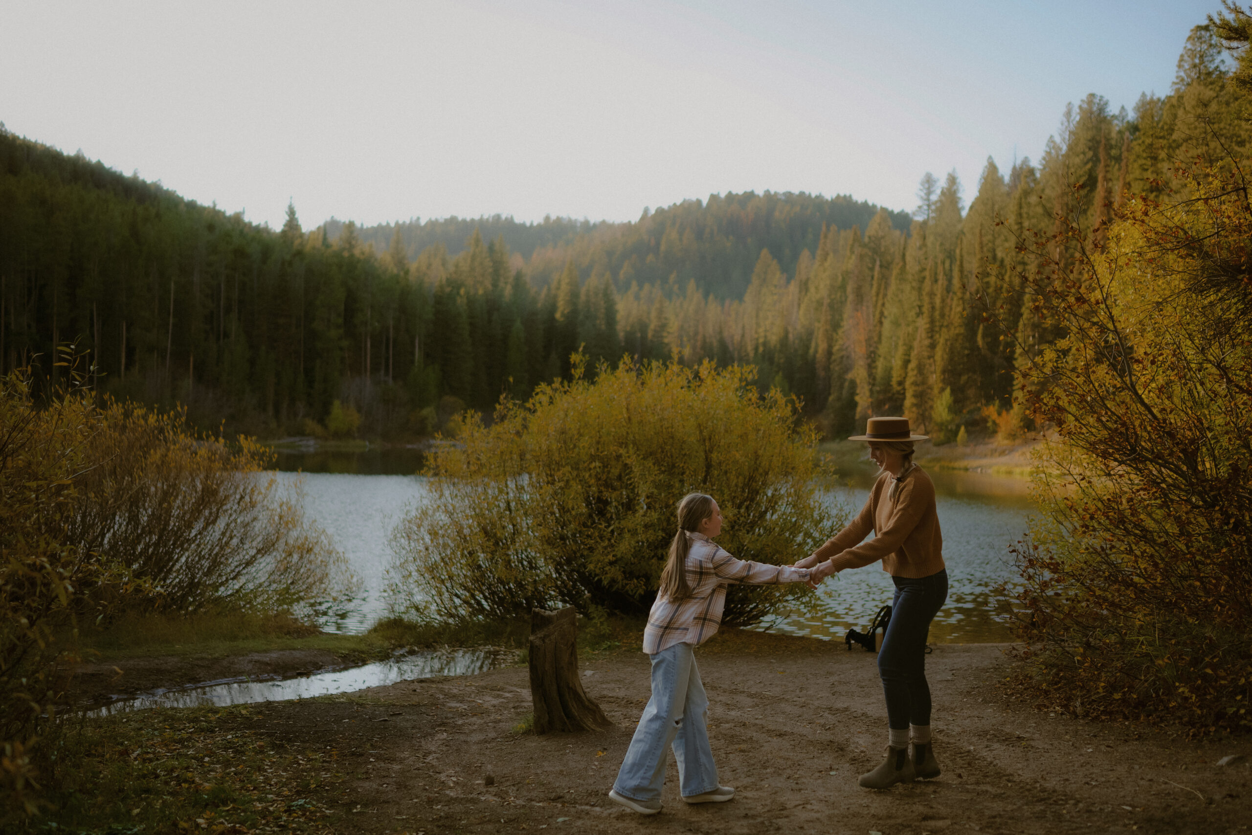 Mother and daughter holding hands in the forest by a lake during a family session by Teton Valley Idaho Newborn Photographer