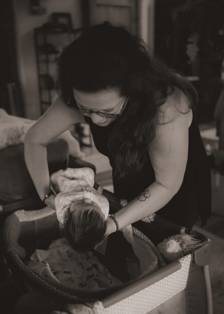 New mom placing baby in crib photographed by Sara O'Connell Newborn Photographer