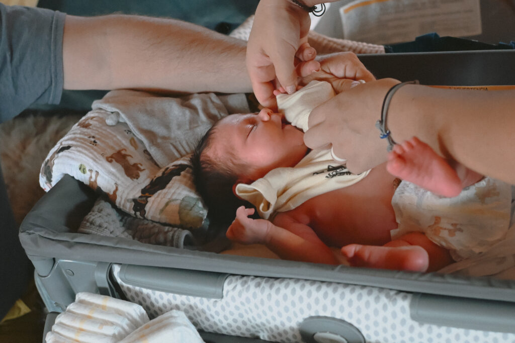 New parents dressing newborn at newborn photography session