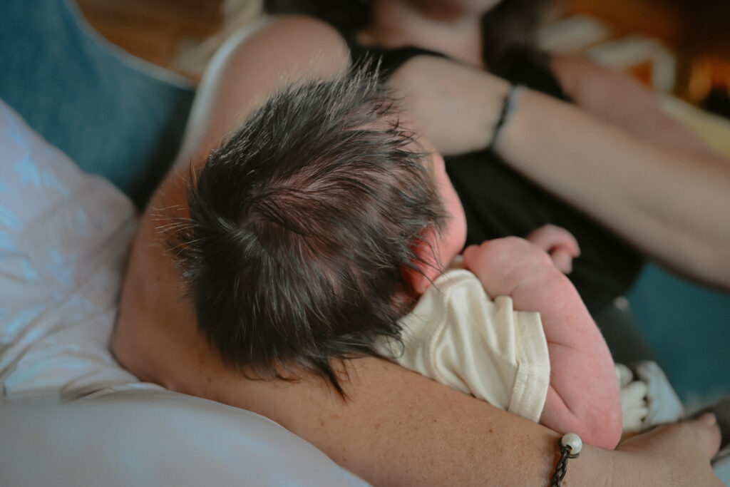 Newborn baby with lots of hair in mamas arms during newborn photography session
