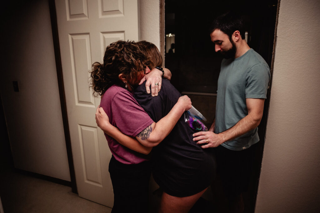 Laboring mother hugging midwife during home birth captured by birth photographer