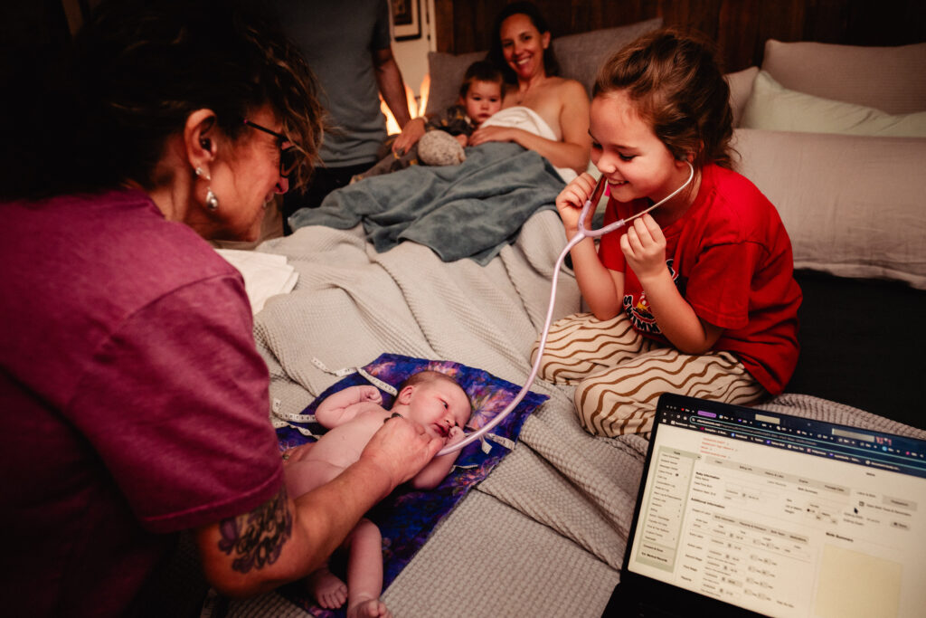 Big sister helping with newborn exam after home birth