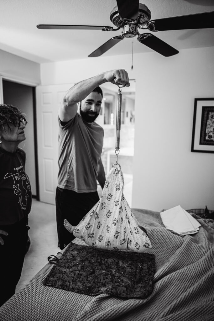 Dad weighing baby after home water birth captured by birth photographer