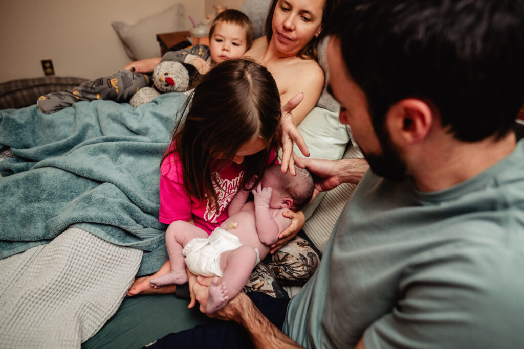 Big sister holding newborn sister at home birth