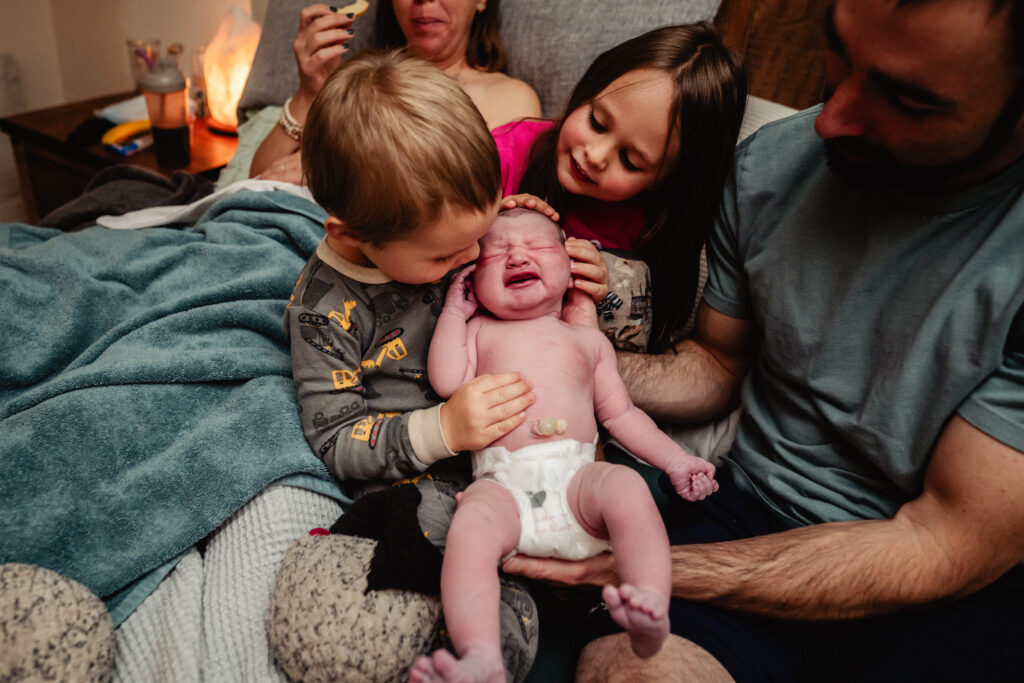 Siblings holding newborn baby after homebirth