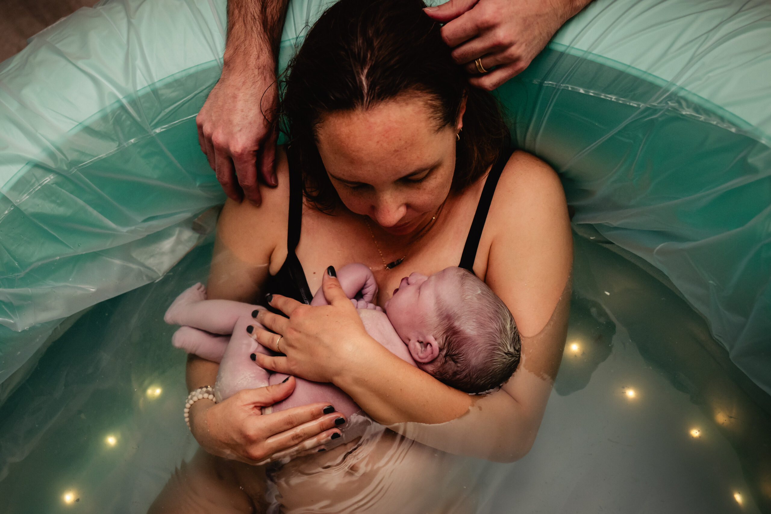Newborn baby being held by mother in the birth pool right after being born