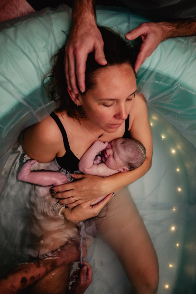 Newborn baby and mother in birth pool captured by birth photographer