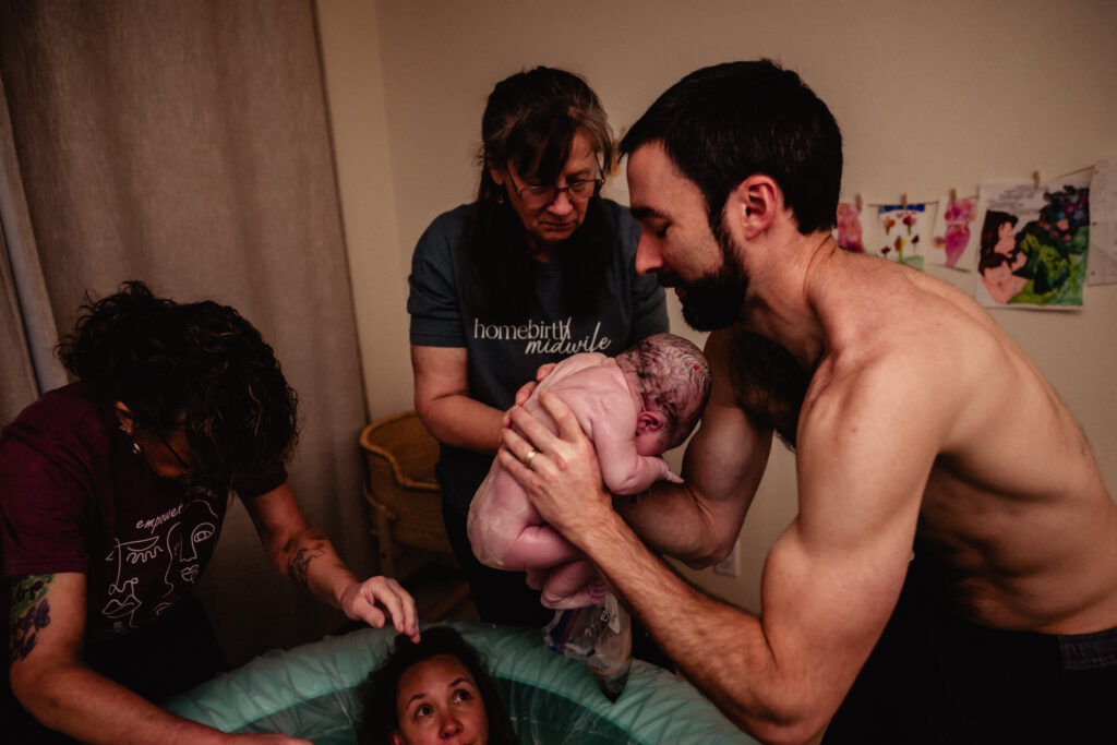 New dad taking baby out of home birth pool