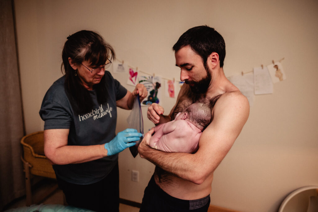 Dad holding new baby and placenta after home birth