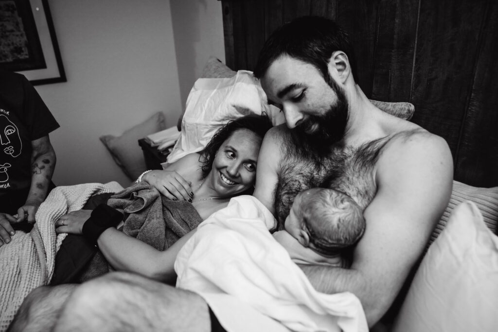 Mom, dad and newborn baby in bed after home birth