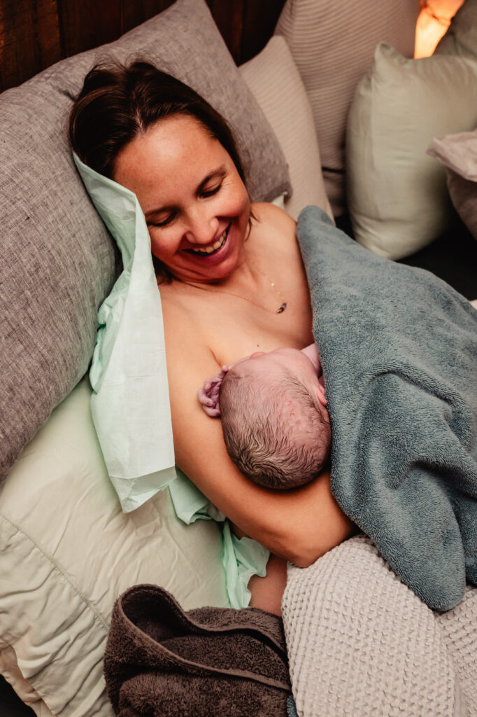Newly postpartum mom holding newborn baby in bed following home birth