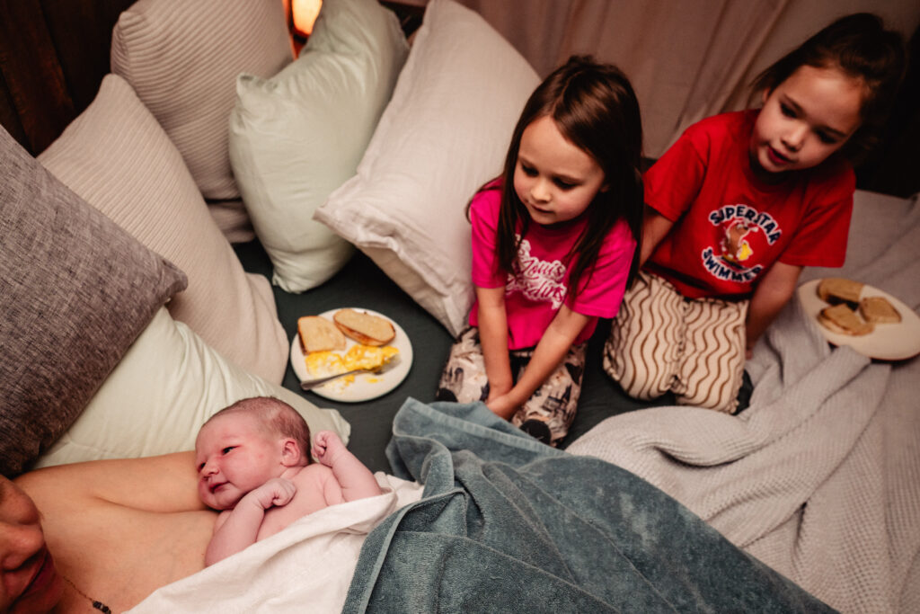 Sisters watching new baby following home birth